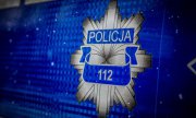 Na niebieskim tle grafika policyjnej odznaki z  napisem Policja i numerem 112.