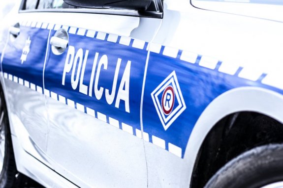 bok radiowozu - na srebrnym kolorze niebieski pas z napisem POLICJA.