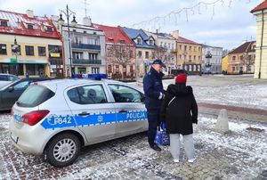 Policjant i Policjantka podczas spotkań na terenie miasta z seniorami. Widoczny radiowóz.