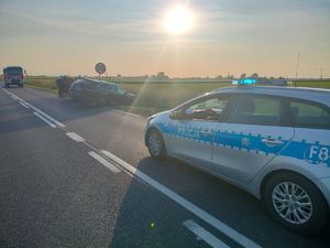 Radiowóz na drodze i pojazdy po zderzeniu poza drogą.