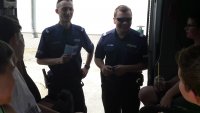 Policjanci przed radiowozem z uczestnikami pikniku.