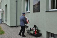 policjant składa kwiaty przed tablicą pamiątkową.