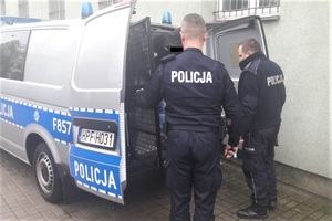 policjanci wprowadzają zatrzymanego do radiowozu.