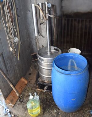 zabezpieczona aparatura, alkohol oraz zacier w beczce.