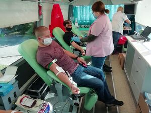 krwiodawcy siedzą na fotelach w ambulansie, którego obsługa prowadzi pobór krwi.