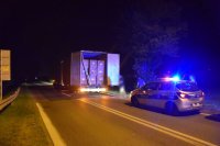 samochód ciężarowy zatrzymany na drodze, za nim radiowóz z włączonymi światłami pojazdu uprzywilejowanego - noc.