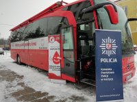 Na pierwszym zdjęciu znajduje się autobus z napisem Mobilny punkt poboru krwi. Po lewej stronie otwartych drzwi usytuowany jest baner koloru biało-czerwonego, na którym widnieje tekst: Nasza krew ratuje życie. Dołącz, zostań honorowym dawcą. HDK PCK Strażak przy OSP w Łęczycy. Po prawej stronie drzwi znajduje się baner koloru granatowego z logo Policji i napisem koloru białego Komenda Powiatowa Policji w Łęczycy.