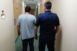 korytarz komendy, policjant w mundurze prowadzi zatrzymanego.