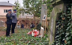Komendant Powiatowy Policji wraz ze strażakiem oddają honory przed tablica nagrobną.