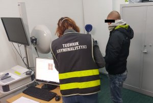 Technik kryminalistyki z podejrzanym podczas daktyloskopii.