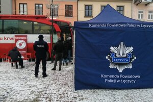 Ambulans do poboru krwi , przed nim krwiodawcy, obok stanowisko promocyjne Policji.