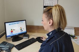 policjantka w mundurze siedzi przed komputerem w biurze.