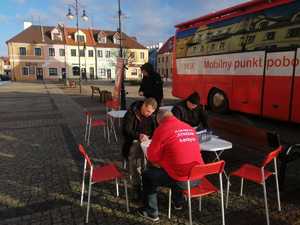 Na zdjęciu osoby wypełniające ankiety przed mobilnym punktem poboru krwi.