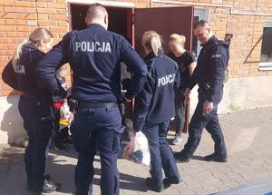 Policjanci w mundurach przekazują paczki rodzinom.