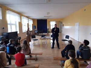 policjant w mundurze podczas rozmowy z uczniami w sali.