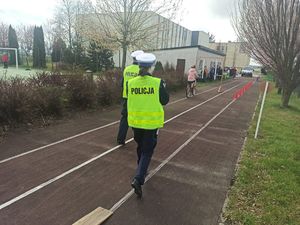 Policjanci podczas konkursu praktycznego oceniają jazdę rowerzystki na torze przeszkód.