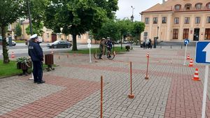 Dziewczyna na rowerze pokonuje tor przeszkód, obok policjantka.