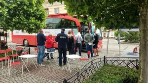 Na placu Kościuszki w Łęczyc zaparkowany krwiobus obok którego stroją osoby do oddania krwi.