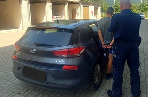 Policjant z zatrzymany obok samochodu służbowego.