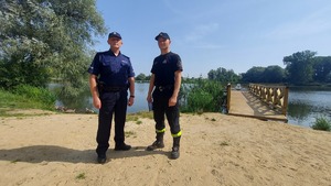 Policjant i strażak stoją przed zalewem.