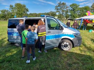 Dzieci z policjantem przed radiowozem na pikniku rodzinnym w Łęczycy.