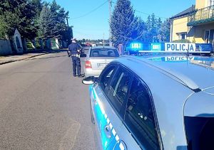 Policjant na drodze kontroluje samochód.