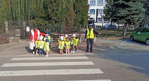 Policjantka z przedszkolakami przed przejściem dla pieszych.