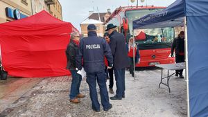 Policjant stoi tyłem i rozmawia z innymi osobami.