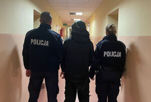 Policjanci z zatrzymanym stoją tyłem.
