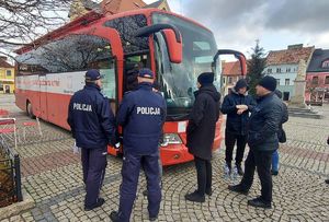 Policjanci stoją przed mobilnym punktem poboru krwi.