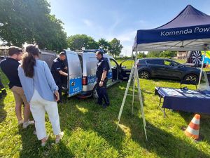 Policjanci na stoisku promocyjnym z odwiedzającymi.