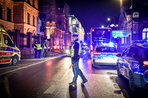 Umundurowany policjant reguluje ruchem na ulicy w porze nocnej.