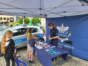 Policjantka na stoisku promocyjnym rozmawia z dziećmi.