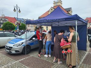 Policjantka na stoisku promocyjnym rozmawia z dziećmi.