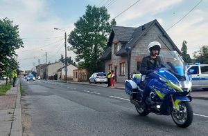 Policjanci, służby porządkowe podczas zabezpieczenia przejazdu wyścigu kolarskiego przez teren ulicy Kutnowskiej w Piątku.