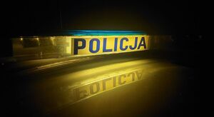 Podświetlony napis Policja w nocnej scenerii.