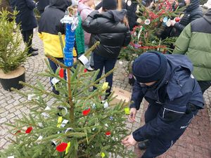 Policjanci zdobią choinkę odblaskami.