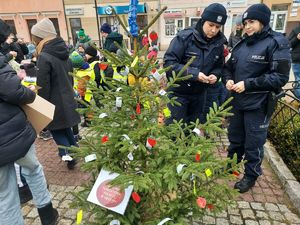 Policjanci zdobią choinkę odblaskami.