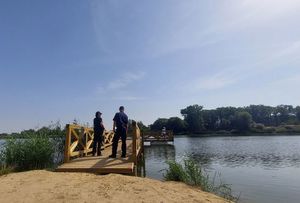 Dwoje policjantów stoi na molo przy akwenie.