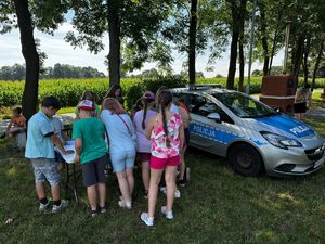 POLICJANTKA Z DZIEĆMI I RADIOWÓZ OBOK.