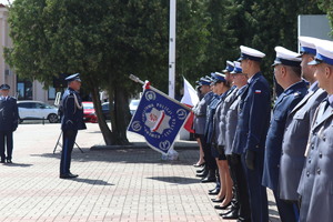 Policjanci w umundurowaniu wyjściowym na placu Tadeusza Kościuszki podczas uroczystości z pocztem sztandarowym i zaproszonymi gośćmi.