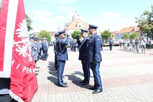 Policjanci w umundurowaniu wyjściowym na placu Tadeusza Kościuszki podczas uroczystości z pocztem sztandarowym i zaproszonymi gośćmi.