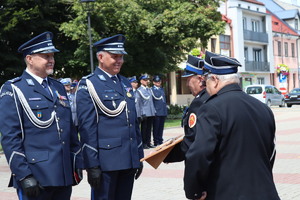 Policjanci w umundurowaniu wyjściowym na placu Tadeusza Kościuszki podczas uroczystości z pocztem sztandarowym i zaproszonymi gośćmi.