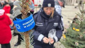 Policjantki wieszają na choince odblaski, w tle młodzież, mikołaj.