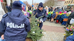 Policjantki wieszają na choince odblaski, w tle młodzież, mikołaj.