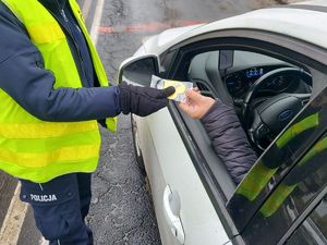 Policjantka rozdaje kierującym serduszka. Policjant z policjantką obok radiowozu.