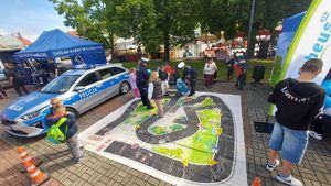 Policjanci, radiowóz i gra edukacyjna z dziećmi na palcu Kościuszki w Łęczycy.