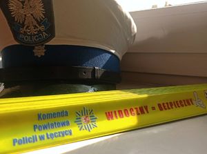 Policjant  i policjantka wręcza odblask. Czapka policyjna z odblaskiem.