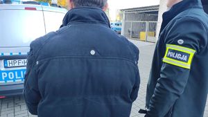 Policjant z zatrzymanym obok radiowozu.