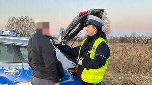 Policjantka prowadzi badanie stanu trzeźwości kierowcy. W tle radiowóz.